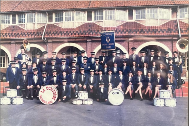 L’harmonie La Concorde en costume bleu marine, avec sa bannière et sa grosse caisse